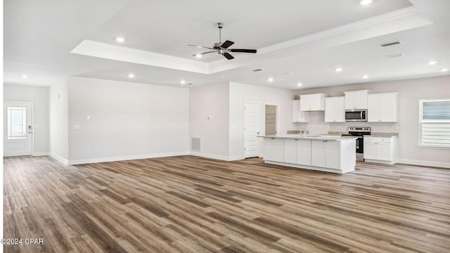 kitchen with open floor plan, appliances with stainless steel finishes, a raised ceiling, and visible vents