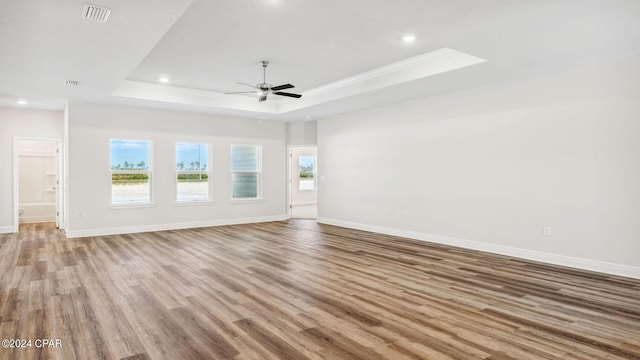 unfurnished living room featuring wood finished floors, visible vents, baseboards, a tray ceiling, and recessed lighting