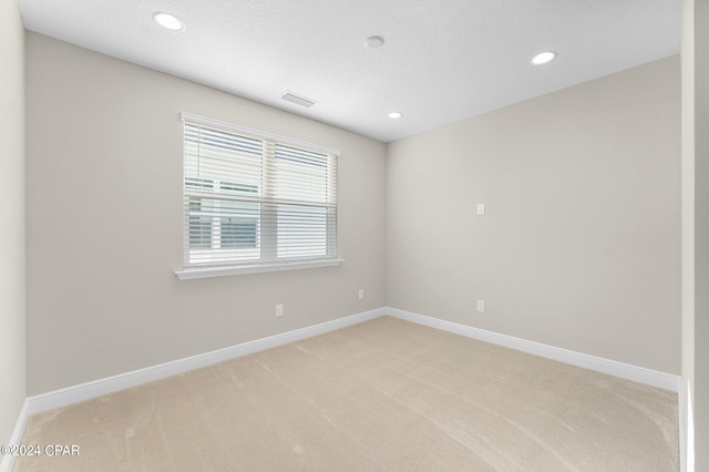 spare room featuring recessed lighting, light carpet, a textured ceiling, and baseboards