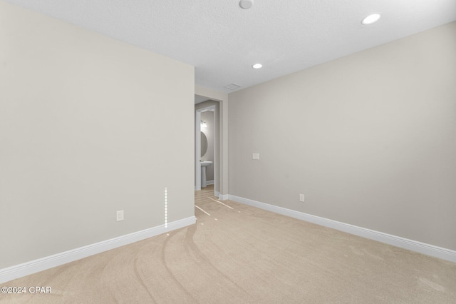 unfurnished room featuring light carpet, baseboards, a textured ceiling, and recessed lighting