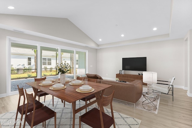 dining space featuring high vaulted ceiling and light hardwood / wood-style flooring