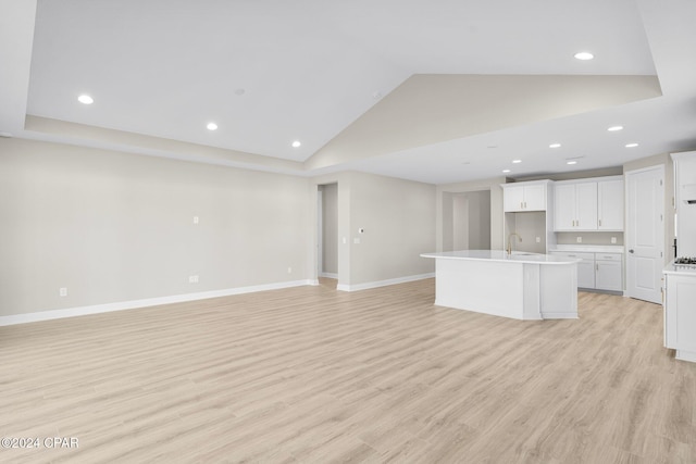 unfurnished living room with sink, high vaulted ceiling, and light hardwood / wood-style flooring