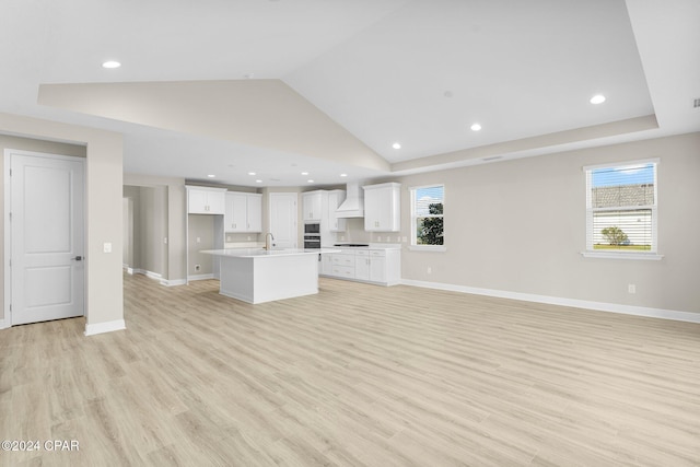 unfurnished living room featuring high vaulted ceiling, a healthy amount of sunlight, sink, and light hardwood / wood-style flooring