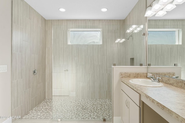 bathroom with vanity, plenty of natural light, and tiled shower