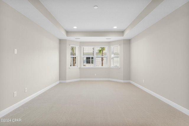 unfurnished room featuring baseboards, recessed lighting, a tray ceiling, and light carpet