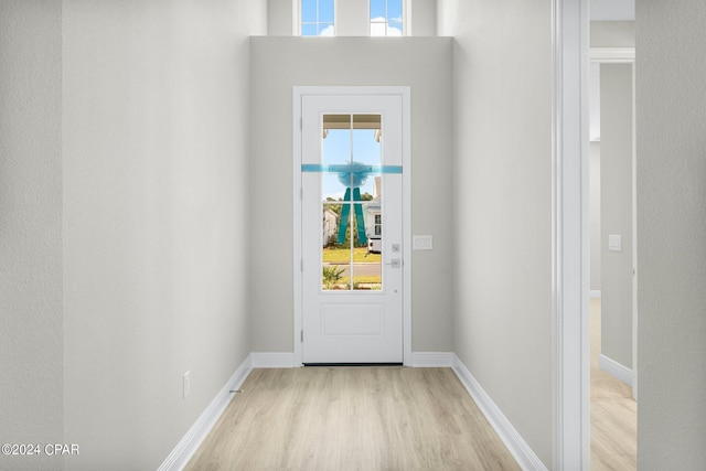 doorway to outside with light wood-type flooring and baseboards