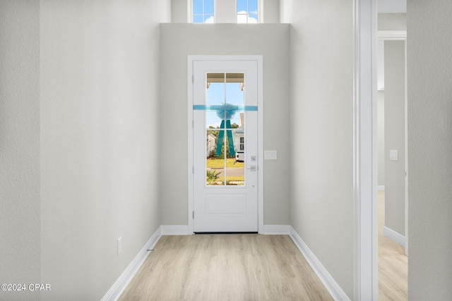 doorway to outside with baseboards, light wood finished floors, and a wealth of natural light