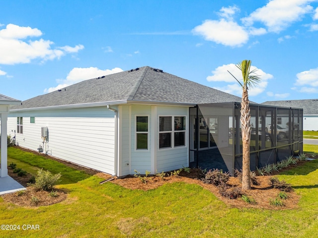 rear view of property featuring a sunroom, roof with shingles, and a yard