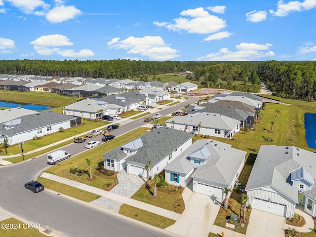 drone / aerial view featuring a water view, a forest view, and a residential view