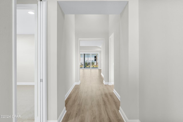 hall with light wood-style floors and baseboards