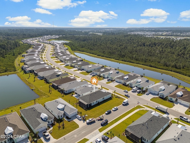 drone / aerial view with a forest view, a residential view, and a water view