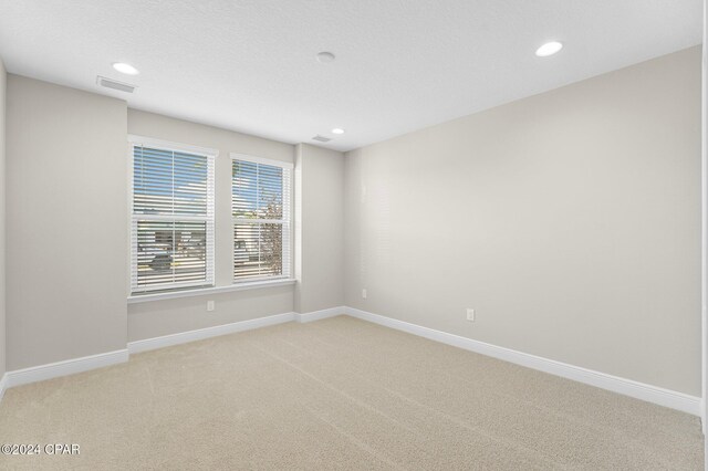 empty room featuring light colored carpet, visible vents, and baseboards