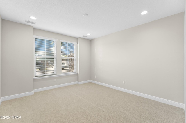 spare room with baseboards, light carpet, recessed lighting, and visible vents