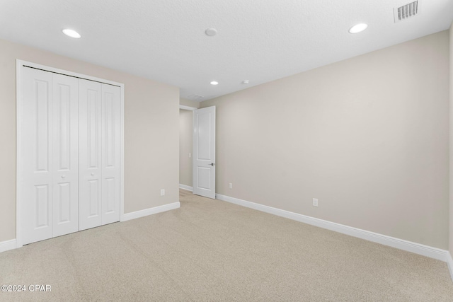 unfurnished bedroom featuring light colored carpet and a closet