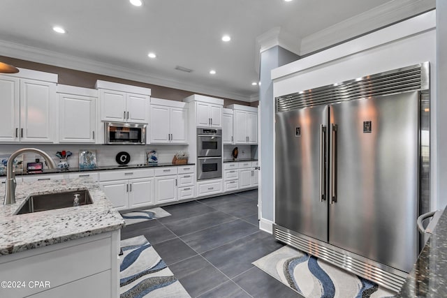 kitchen featuring light stone countertops, sink, white cabinets, and stainless steel appliances