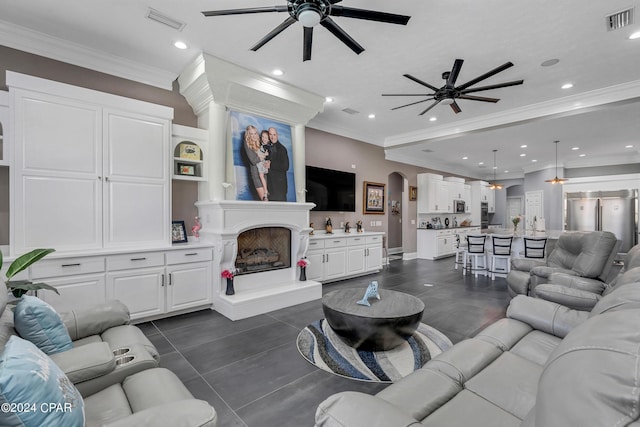 living room with ceiling fan, dark tile patterned flooring, and ornamental molding