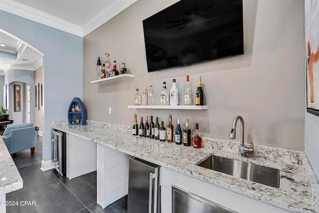 bar featuring beverage cooler, light stone countertops, sink, and ornamental molding