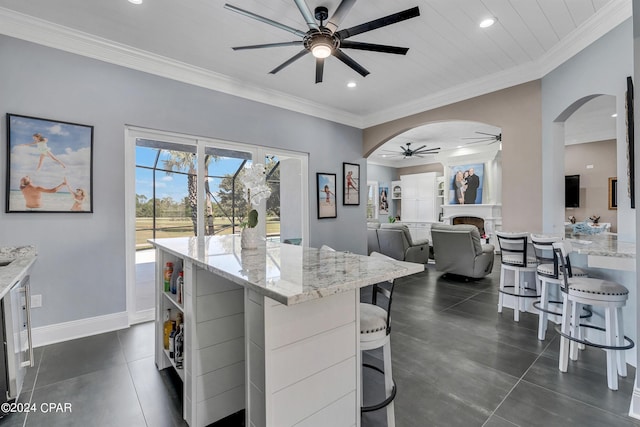 kitchen with light stone counters, white cabinetry, a center island, and a breakfast bar area