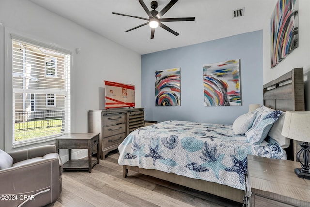 bedroom with ceiling fan, multiple windows, and light hardwood / wood-style floors