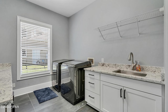 clothes washing area featuring cabinets, tile patterned floors, washing machine and clothes dryer, and sink