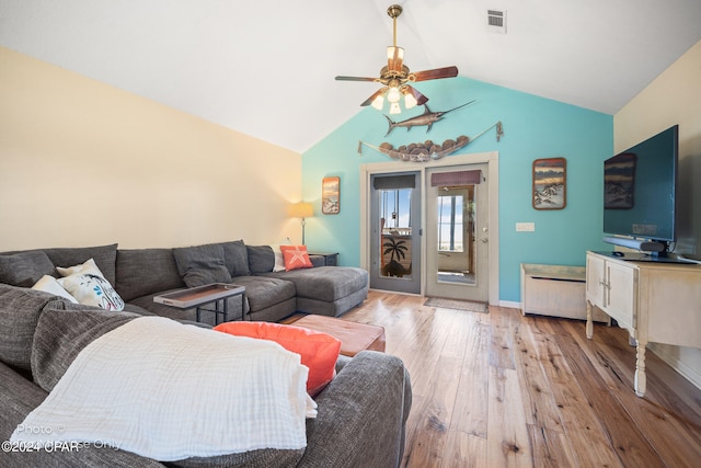 living room with ceiling fan, vaulted ceiling, and light wood-type flooring