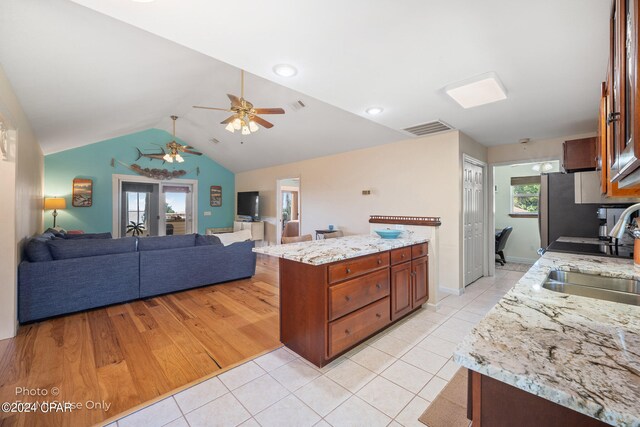 kitchen featuring light stone countertops, ceiling fan, sink, light hardwood / wood-style flooring, and lofted ceiling