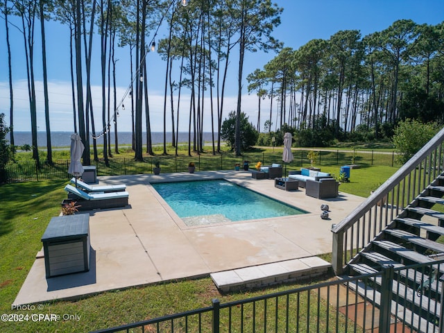 view of pool with outdoor lounge area, a patio area, and a lawn