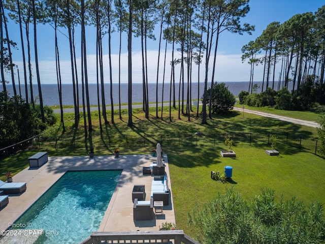 view of pool with an outdoor living space, a water view, a patio, and a lawn