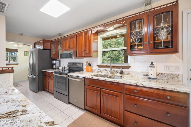 kitchen with decorative backsplash, light stone countertops, sink, and appliances with stainless steel finishes