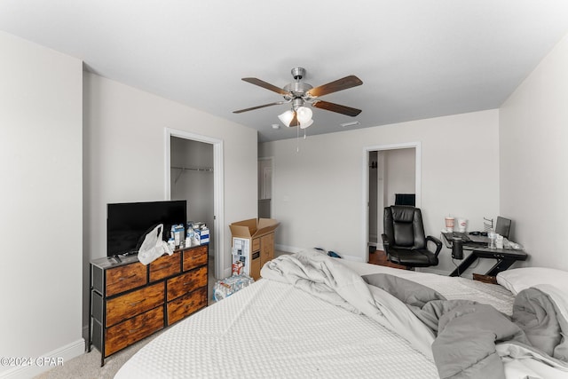 bedroom featuring a spacious closet, a closet, ceiling fan, and carpet