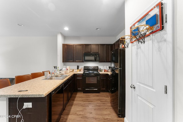 kitchen with sink, kitchen peninsula, a breakfast bar, and black appliances