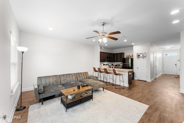 living room with ceiling fan and light wood-type flooring