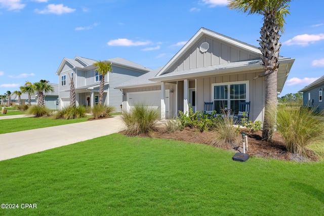 view of front of property featuring a front yard, a garage, and a porch