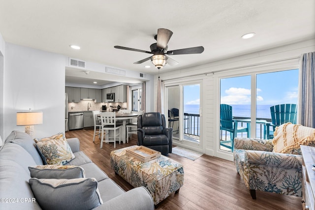 living room with a water view, sink, dark hardwood / wood-style flooring, and ceiling fan