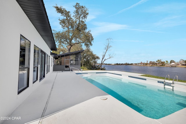 view of swimming pool with a sunroom, a water view, and a patio area