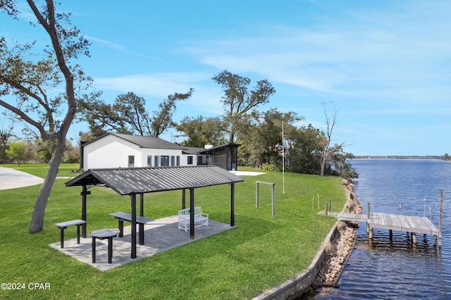 view of dock with a yard, a water view, and a patio area