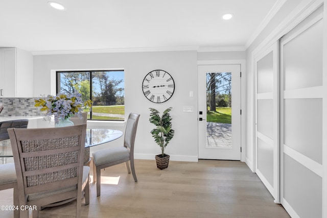 dining area featuring ornamental molding, a wealth of natural light, and light hardwood / wood-style flooring