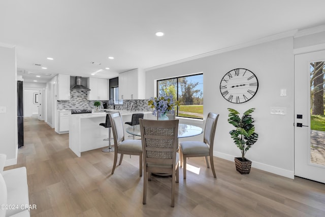 dining space with ornamental molding and light hardwood / wood-style floors