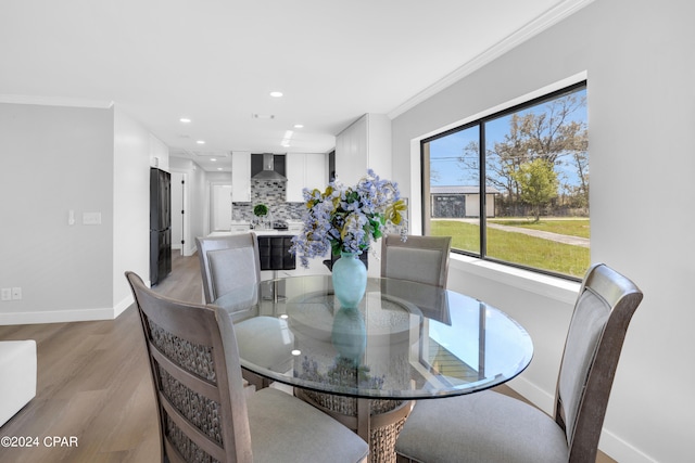 dining space with ornamental molding and light wood-type flooring