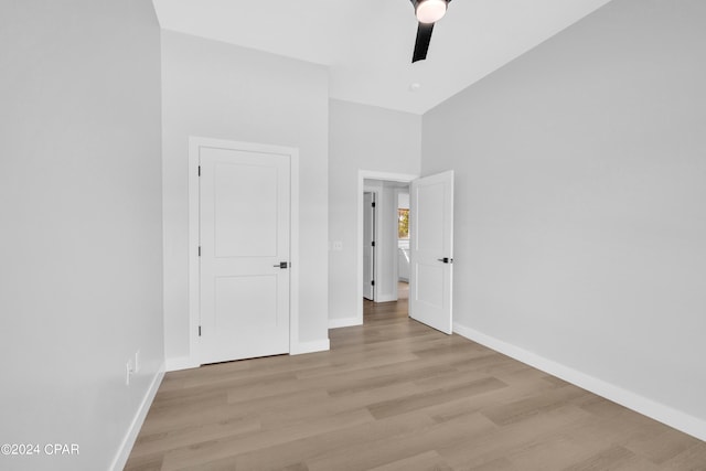 unfurnished bedroom featuring light wood-type flooring, ceiling fan, and a towering ceiling