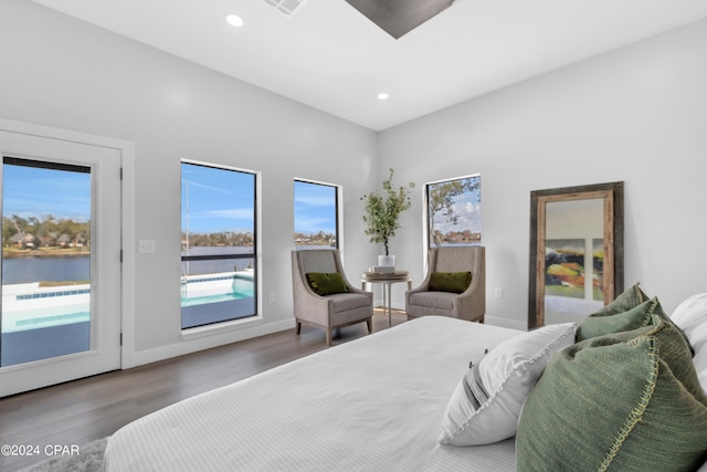 bedroom with access to outside, hardwood / wood-style floors, and a water view