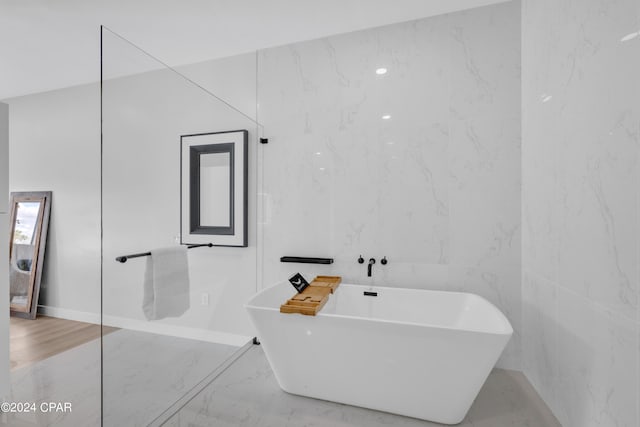 bathroom featuring a bath and tile walls