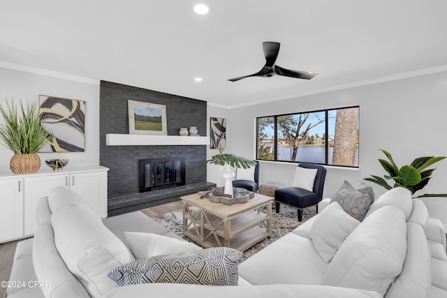 living room with light hardwood / wood-style flooring, ceiling fan, a water view, a fireplace, and ornamental molding