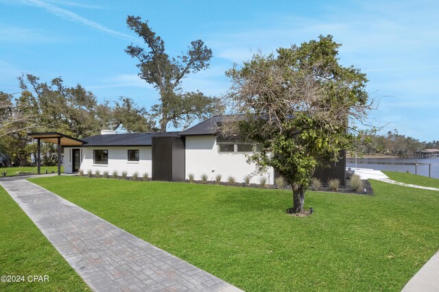 ranch-style house featuring a front lawn and a water view