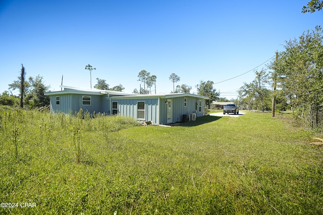 rear view of house featuring board and batten siding and a yard