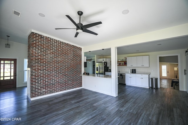 unfurnished living room featuring lofted ceiling, ceiling fan, a healthy amount of sunlight, brick wall, and dark wood-type flooring