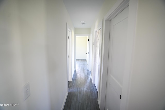 corridor featuring baseboards and dark wood-style floors