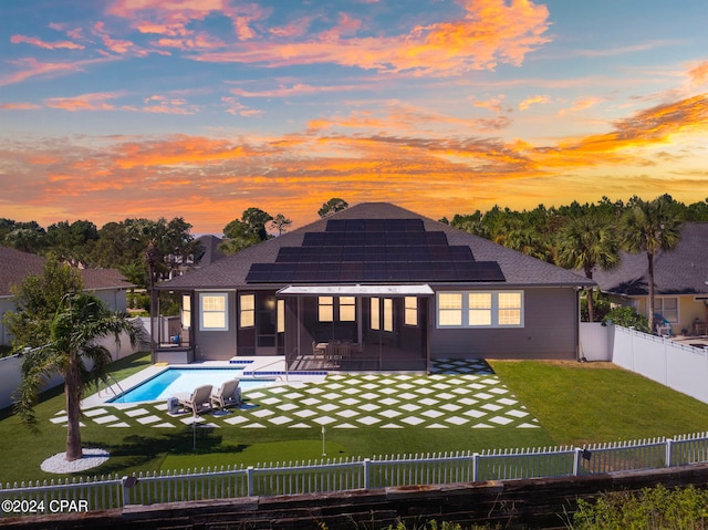 back house at dusk featuring a fenced in pool, a patio area, solar panels, a lawn, and a sunroom