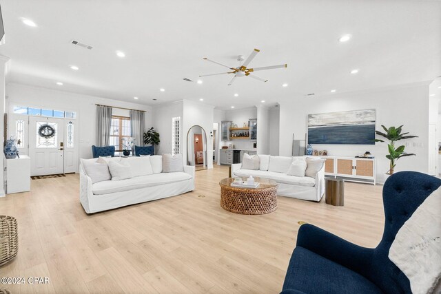 living room featuring crown molding, ceiling fan, and light hardwood / wood-style floors