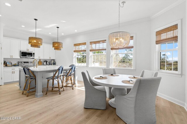 dining area with an inviting chandelier, ornamental molding, and light hardwood / wood-style flooring